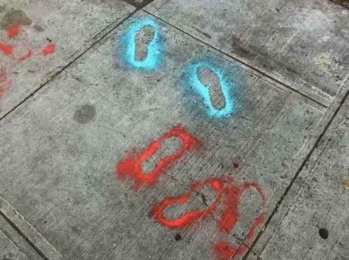 Red and blue footprints, painted on a pavement street, Brooklyn, United States. Photo by Lance Grandahl for Unsplash.